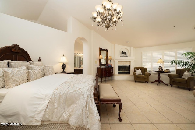 bedroom featuring light tile patterned floors, a chandelier, arched walkways, lofted ceiling, and a glass covered fireplace