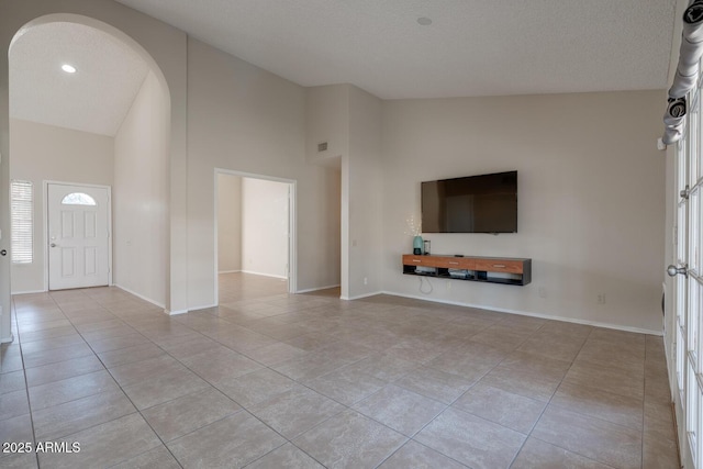 unfurnished living room featuring high vaulted ceiling, a textured ceiling, and light tile patterned floors