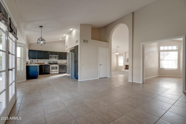 interior space with light tile patterned flooring, high vaulted ceiling, sink, and a textured ceiling