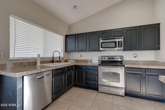 kitchen featuring vaulted ceiling, light tile patterned flooring, sink, stainless steel appliances, and a textured ceiling