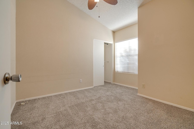 carpeted spare room with ceiling fan, vaulted ceiling, and a textured ceiling