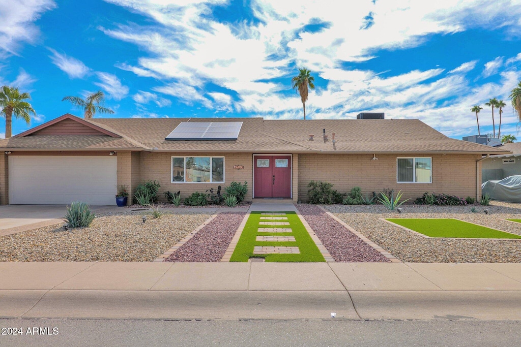 single story home with a garage and solar panels