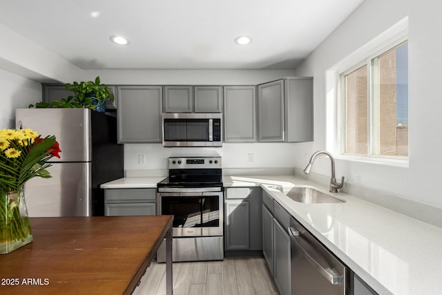 kitchen featuring stainless steel appliances, recessed lighting, a sink, and gray cabinetry