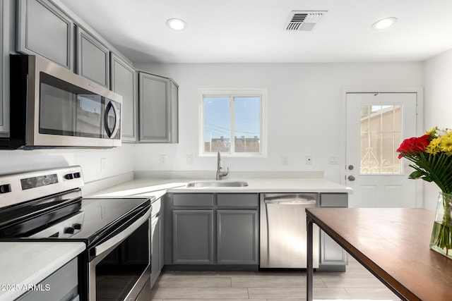 kitchen with visible vents, stainless steel appliances, a sink, and gray cabinetry