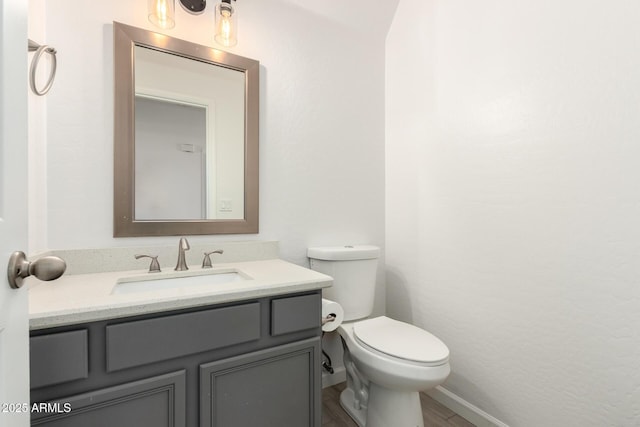 bathroom featuring toilet, vanity, and baseboards