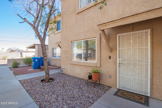 doorway to property with a patio area, fence, and stucco siding