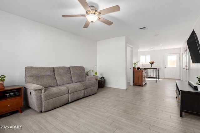 living area featuring a ceiling fan, light wood-type flooring, visible vents, and baseboards