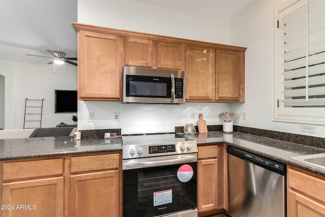 kitchen featuring ceiling fan, appliances with stainless steel finishes, and dark stone counters