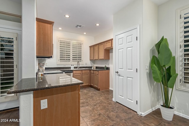 kitchen with dark stone counters, sink, stainless steel dishwasher, kitchen peninsula, and beverage cooler