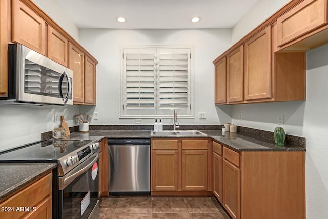 kitchen featuring dark stone countertops, sink, dark tile patterned floors, and stainless steel appliances