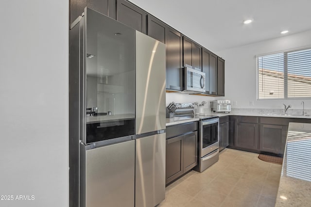 kitchen with appliances with stainless steel finishes, dark brown cabinets, and sink