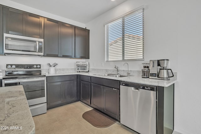 kitchen with light stone countertops, dark brown cabinetry, stainless steel appliances, sink, and light tile patterned floors