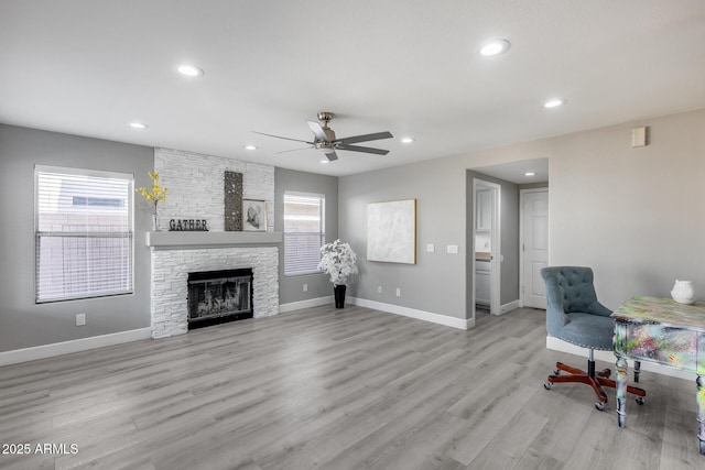 living room with ceiling fan, a fireplace, and light wood-type flooring