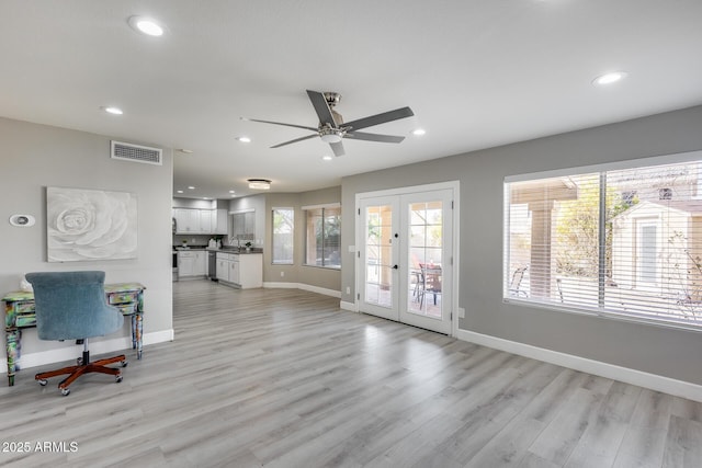 living room featuring ceiling fan, sink, light hardwood / wood-style floors, and french doors