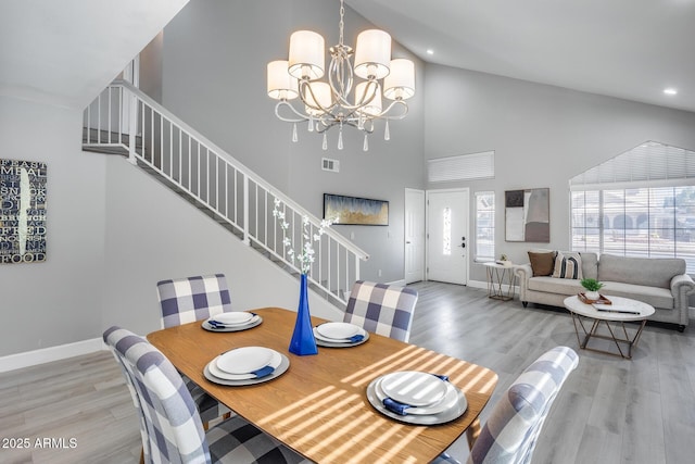 dining area with high vaulted ceiling, a chandelier, and light wood-type flooring