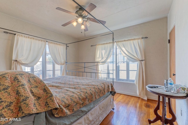 bedroom with ceiling fan, multiple windows, and hardwood / wood-style flooring