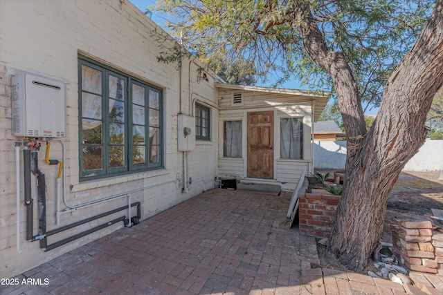 doorway to property with water heater and a patio