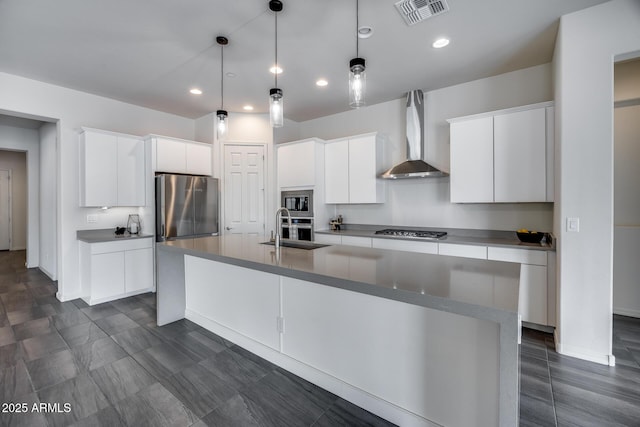 kitchen with a spacious island, visible vents, wall chimney range hood, stainless steel appliances, and a sink