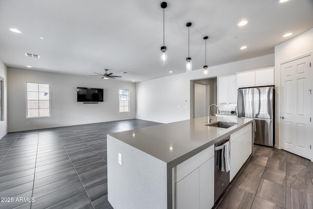 kitchen with decorative light fixtures, appliances with stainless steel finishes, white cabinetry, a ceiling fan, and a sink
