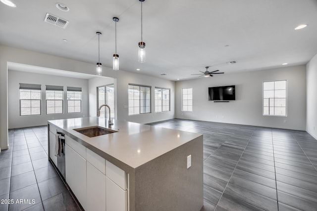 kitchen with a ceiling fan, visible vents, dark tile patterned flooring, a sink, and open floor plan