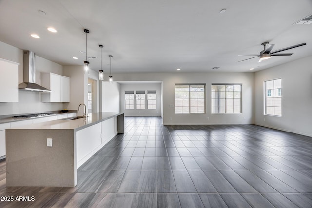 kitchen with visible vents, ceiling fan, open floor plan, white cabinetry, and wall chimney exhaust hood