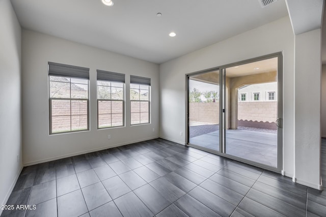 empty room featuring dark tile patterned floors, visible vents, recessed lighting, and baseboards