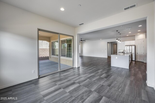 unfurnished living room with a sink, visible vents, and recessed lighting