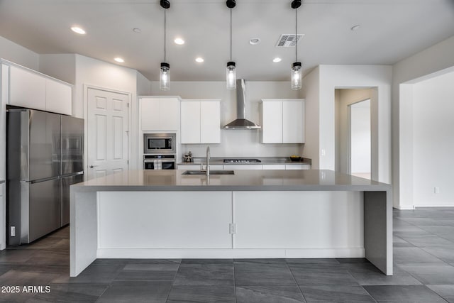 kitchen with visible vents, wall chimney range hood, appliances with stainless steel finishes, white cabinetry, and a sink