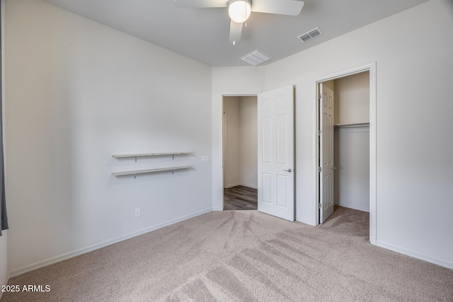unfurnished bedroom featuring visible vents, a walk in closet, a ceiling fan, carpet floors, and baseboards