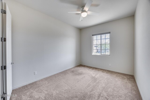 carpeted empty room featuring baseboards and ceiling fan