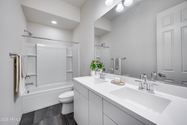 bathroom with double vanity, toilet,  shower combination, and a sink