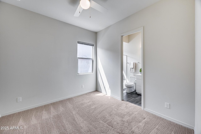 unfurnished bedroom featuring carpet flooring, ensuite bath, baseboards, and a ceiling fan