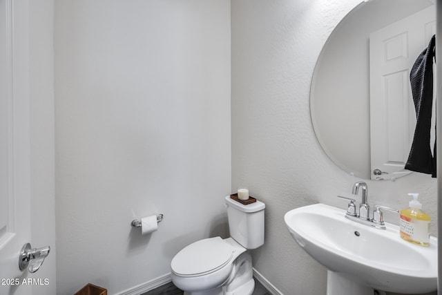 bathroom with toilet, baseboards, and a sink