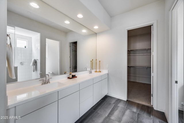 bathroom with a sink, a spacious closet, recessed lighting, and double vanity