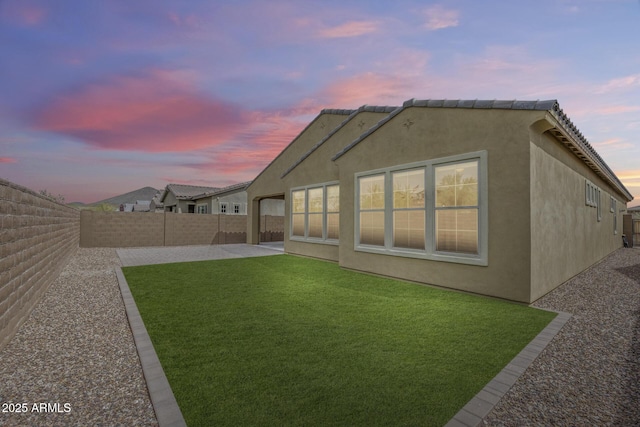 rear view of house with a patio area, stucco siding, a yard, and a fenced backyard