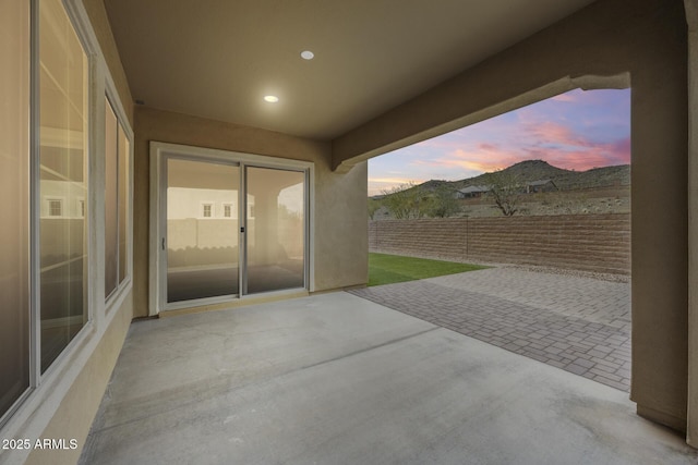 patio terrace at dusk featuring fence