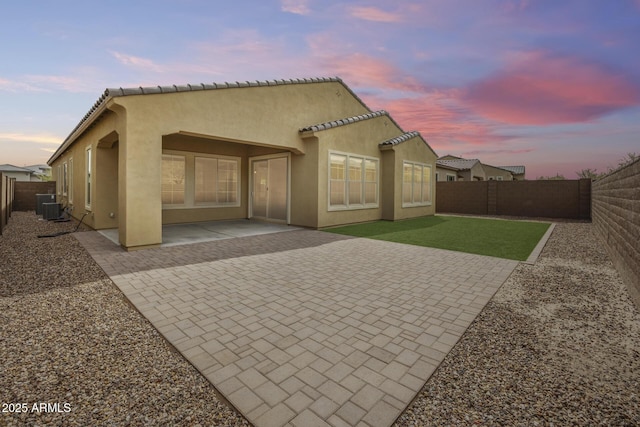 rear view of property with a tiled roof, stucco siding, cooling unit, a fenced backyard, and a patio