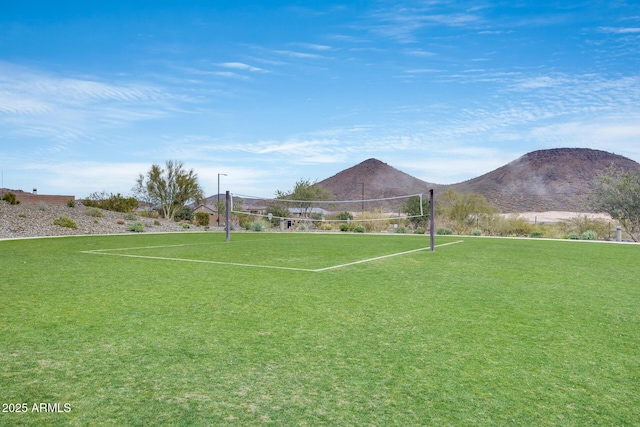 view of property's community featuring volleyball court, a mountain view, and a yard