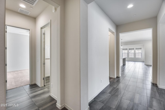 hall featuring dark tile patterned flooring, recessed lighting, and visible vents