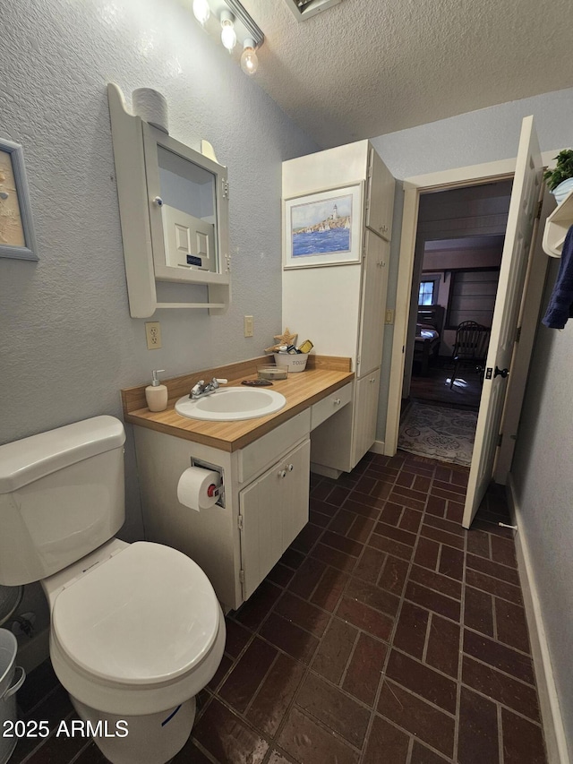 bathroom featuring a textured ceiling, vanity, and toilet