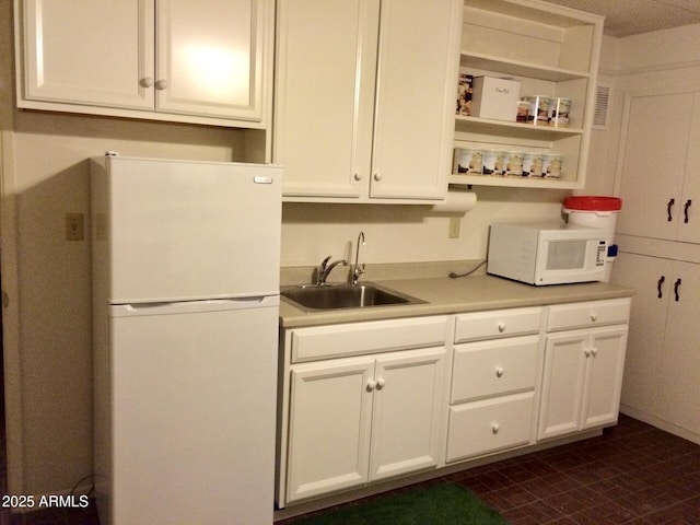 kitchen with white appliances, white cabinetry, and sink