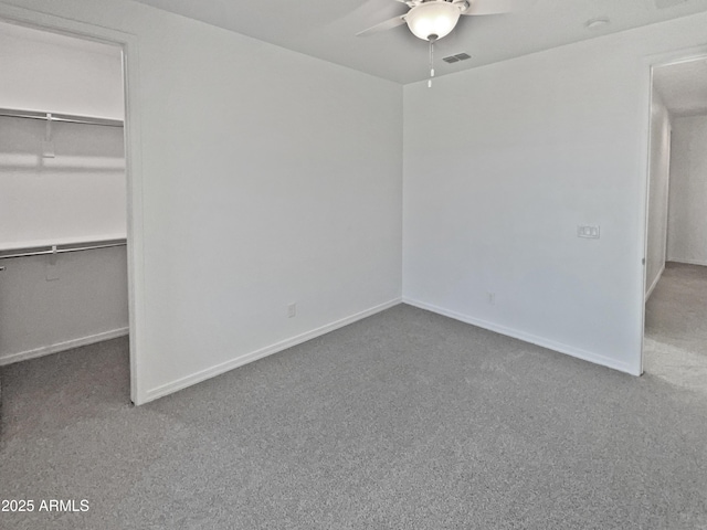 unfurnished bedroom with a walk in closet, carpet floors, a closet, and ceiling fan