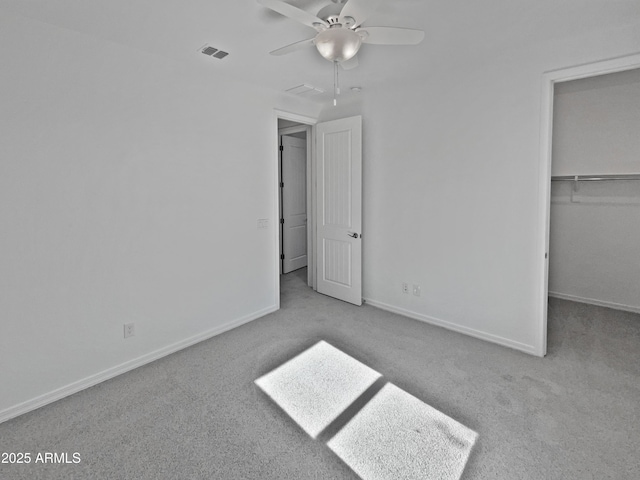 unfurnished bedroom with a walk in closet, light carpet, ceiling fan, and a closet