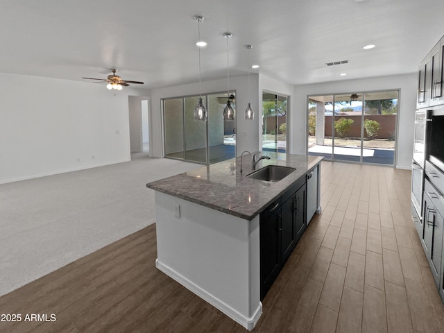 kitchen with dark wood-type flooring, decorative light fixtures, sink, and dark stone countertops