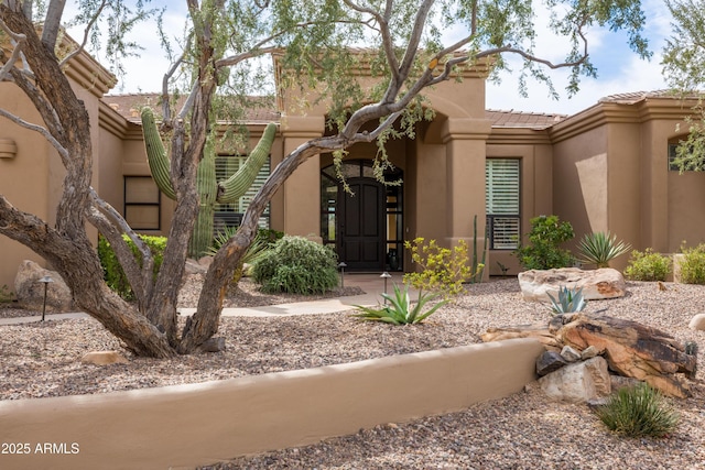 property entrance with a tile roof and stucco siding