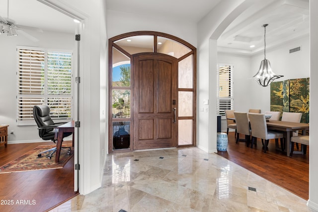 entryway with arched walkways, visible vents, marble finish floor, and baseboards