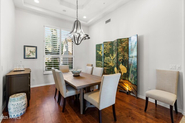 dining room with dark wood finished floors, a tray ceiling, and visible vents