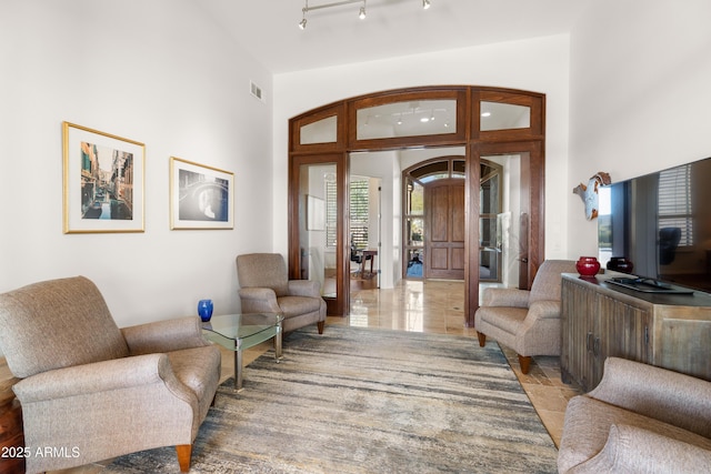 foyer with visible vents, arched walkways, a high ceiling, and rail lighting