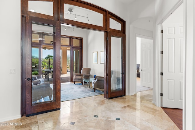 foyer with french doors, baseboards, and rail lighting