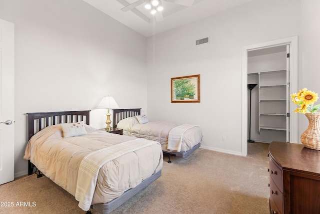 bedroom featuring a spacious closet, visible vents, baseboards, light colored carpet, and a closet